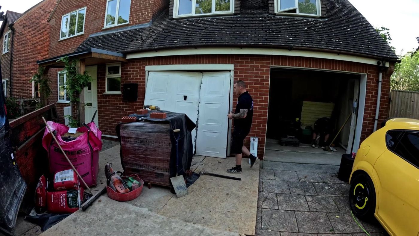 Garage conversion in Swindon before work started - original up-and-over garage doors being removed by SwiftBrick Ltd