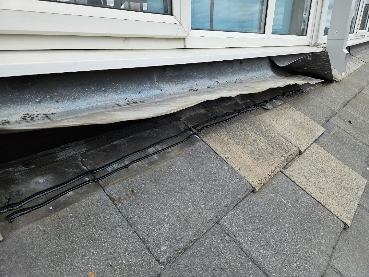 Failed lead flashing lifted away from a window sill on a church hall roof in Gorse Hill