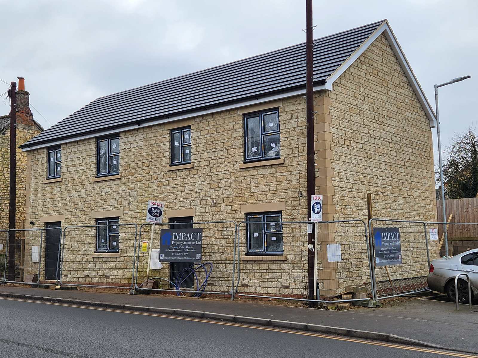 Completed pair of stone-built semi-detached new homes with slate-grey roofs