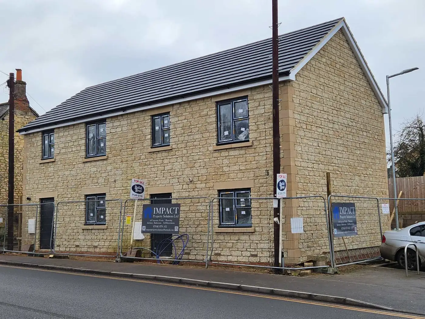 Completed pair of stone-built semi-detached new homes with slate-grey roofs