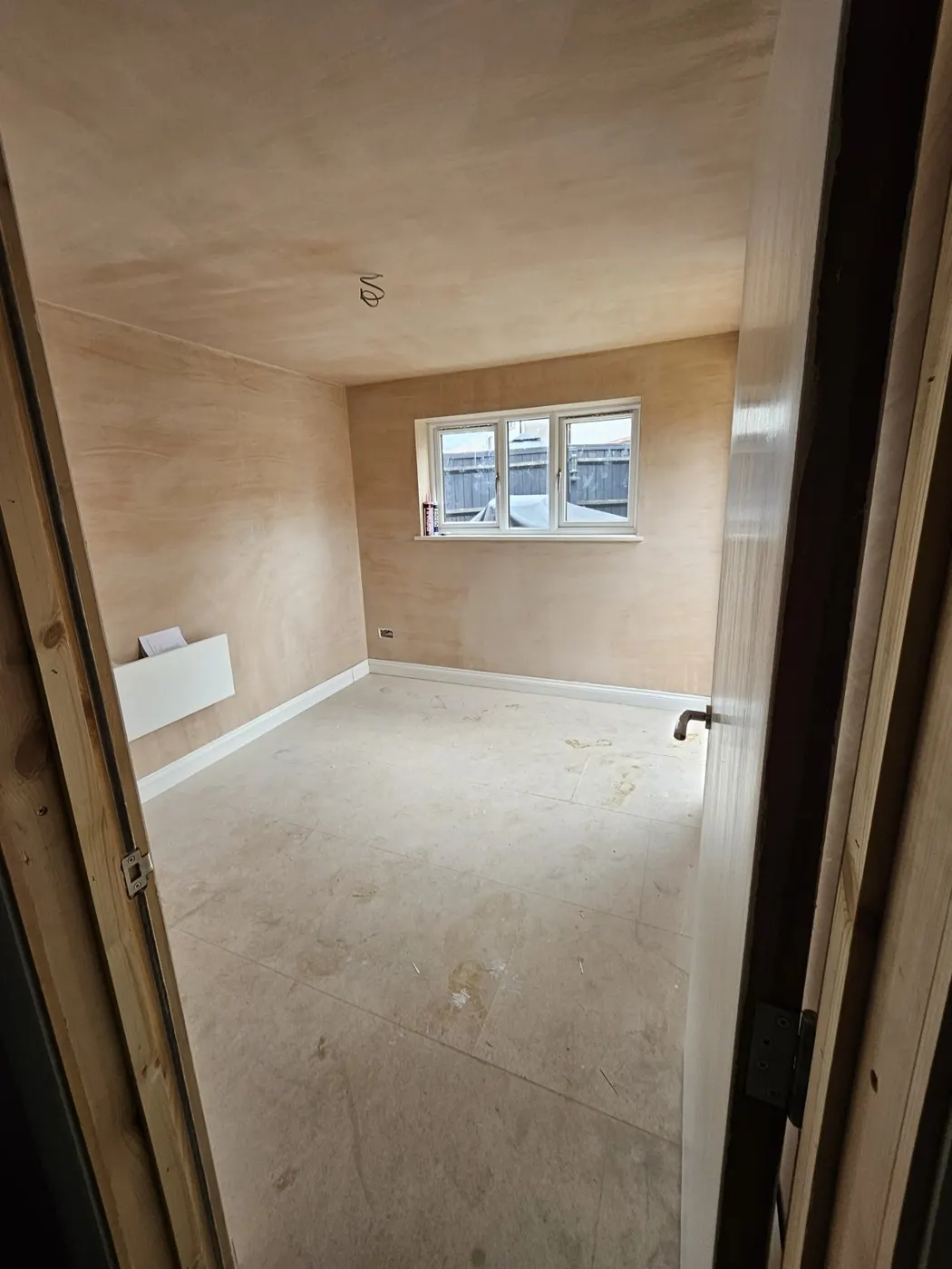 Inside the garden building freshly plastered with skirting and floor down