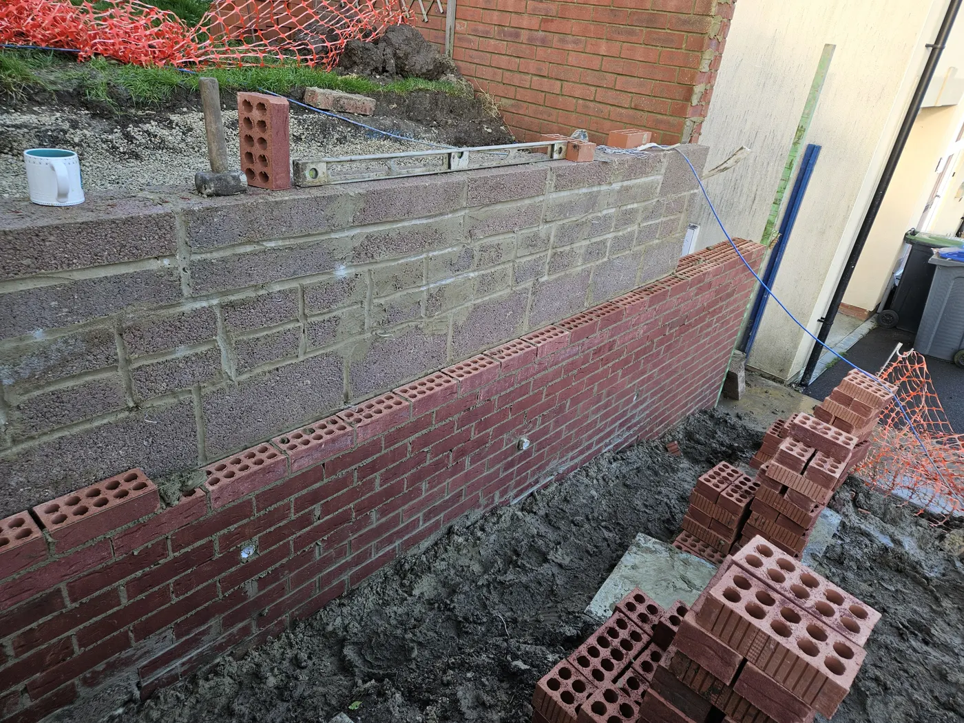 New wall rising in blockwork with a facing-brick outer skin