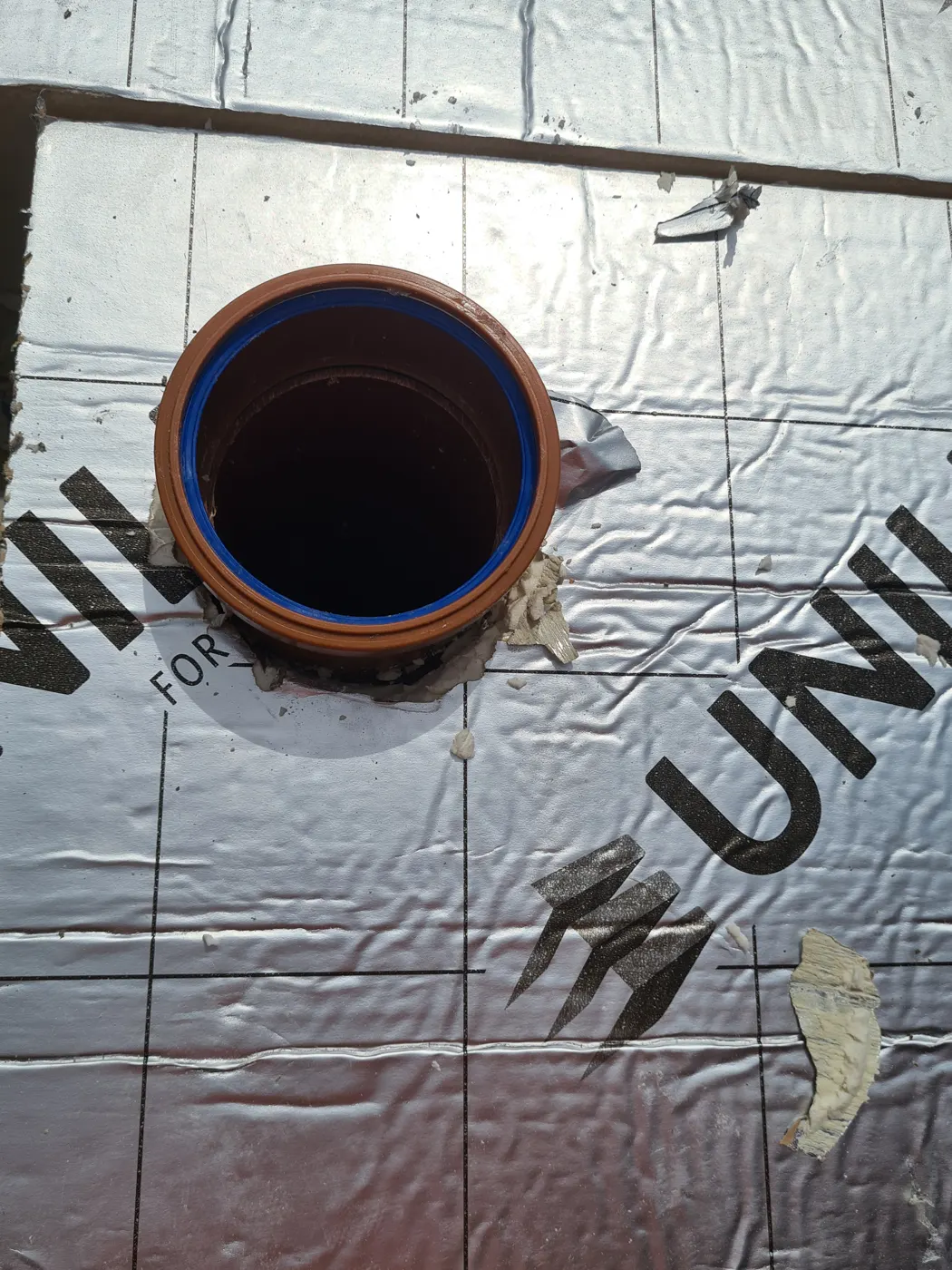 Floor insulation laid over the membrane around a drainage upstand