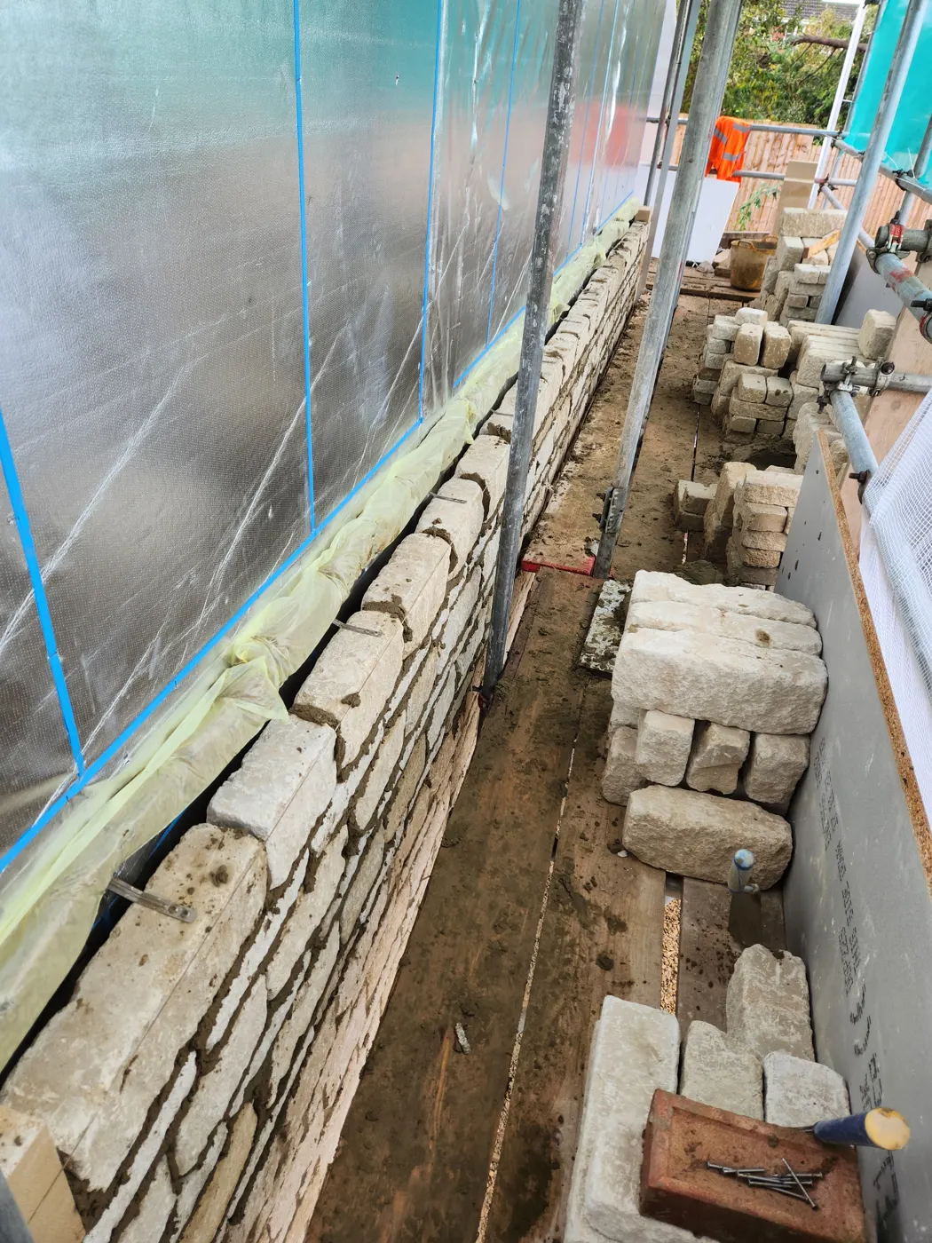 Stone outer skin rising under scaffold against the timber frame