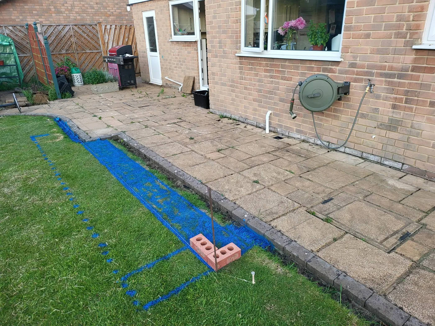 Extension footprint marked out in blue line paint across the old patio