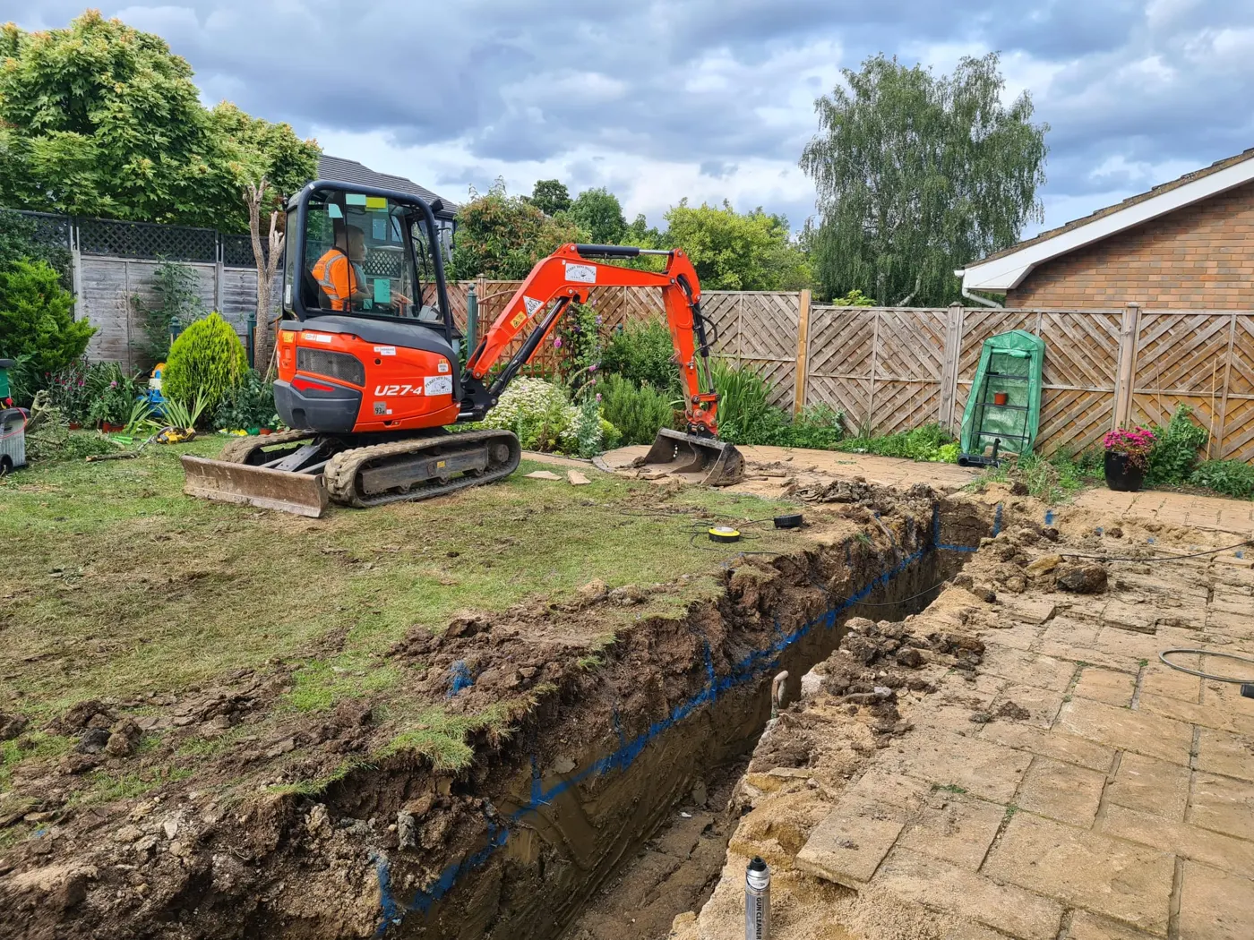 Mini digger excavating the foundation trench behind the house