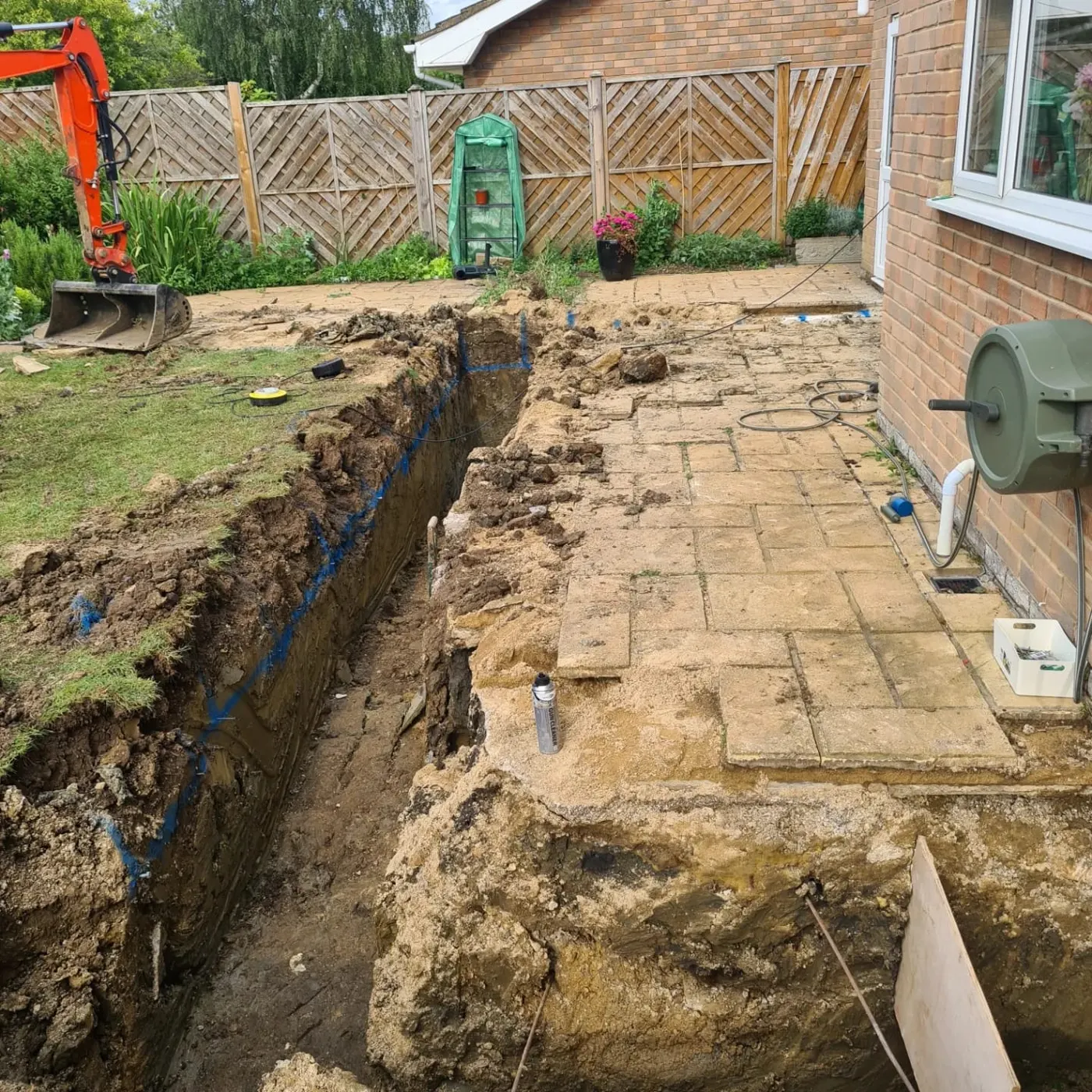 Excavated foundation trench alongside the existing patio slabs