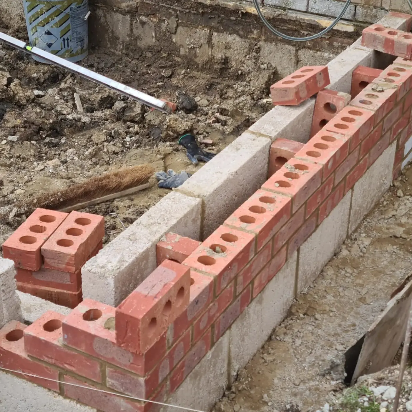 Footing blockwork and reclaimed facing brick rising out of the concrete foundation