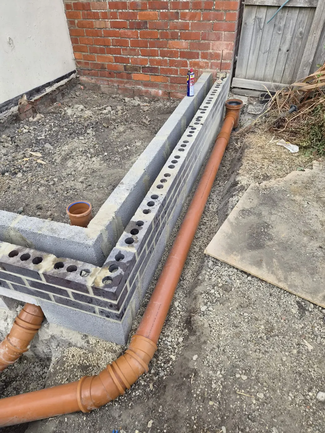 Trench-block footing with a new drain pipe passing through a sleeve