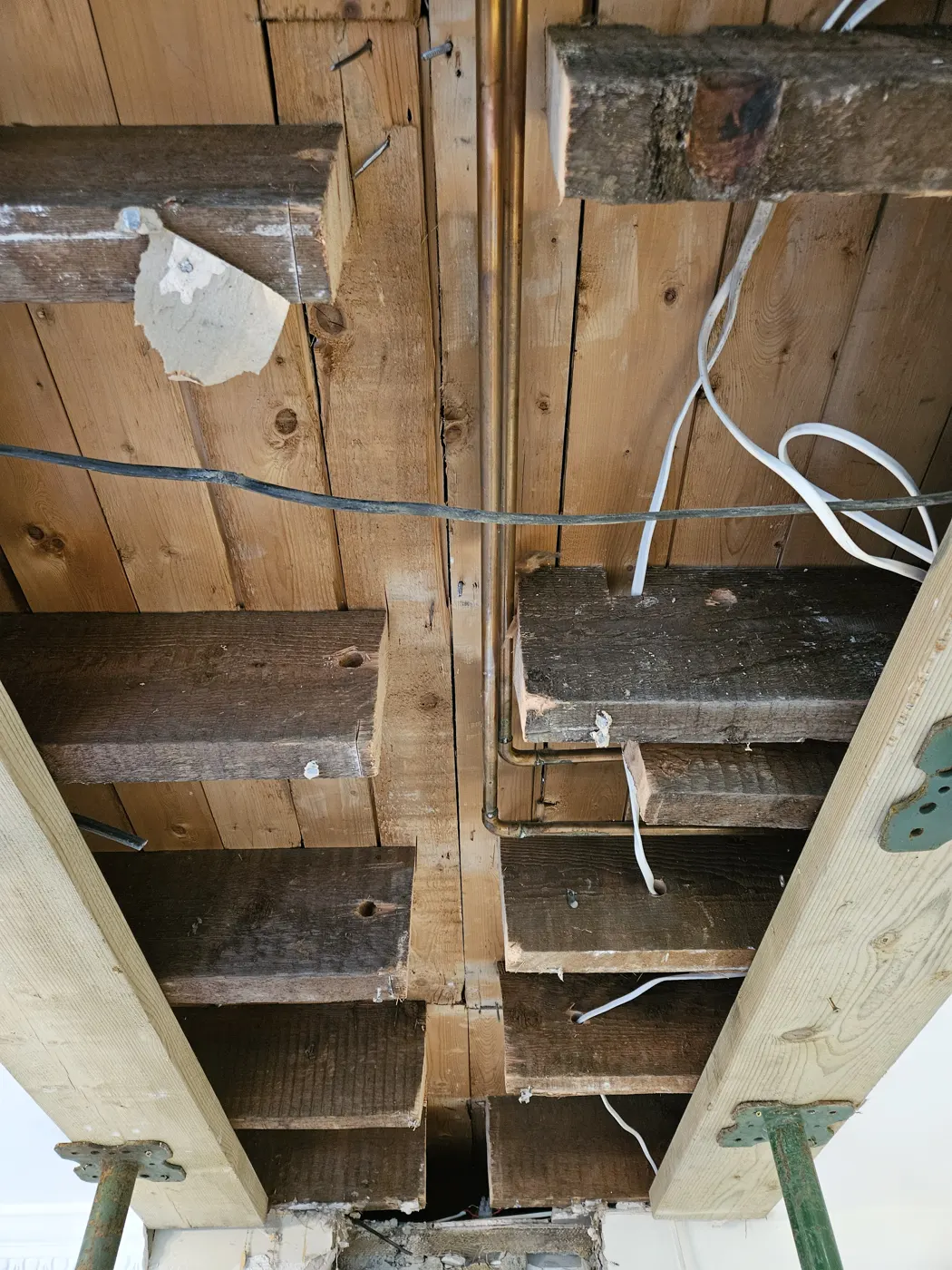 Ceiling opened to expose the floor joists above the wall being removed